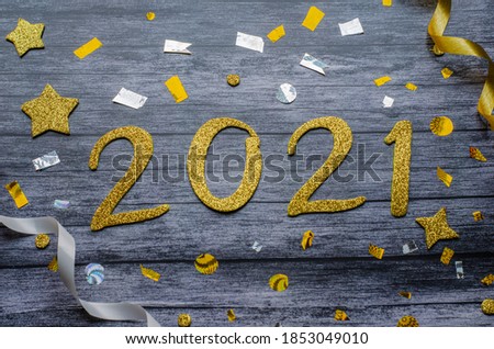 background to black wood and a big golden number 2021 concerning the new year and with golden and silver confetti, serpentines, and stars 