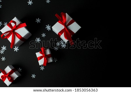 White gifts with red ribbons flat lay. Set of gift box isolated on black background.Christmas gift boxes. Merry Christmas and Happy Holidays greeting card, frame, banner. New Year. Snoflakes