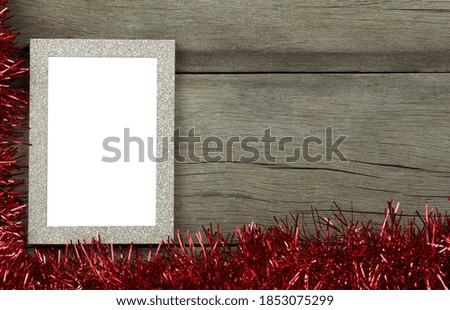 Empty vintage photo frame on wooden floor and red tassels for Christmas and New Year decorations.