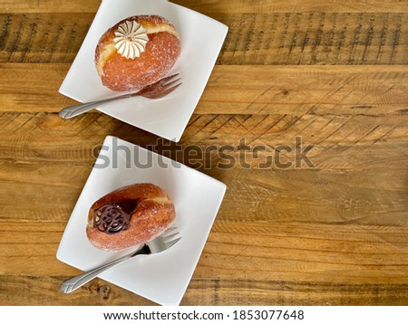 Filled doughnuts decorated with meringue and chocolate served on square plates