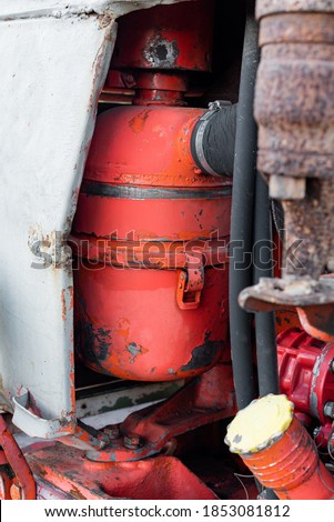 Closeup of coolant reservoir in old vibrant red rusty russian tractor engine on sunny autumn day sharp detail of agriculture machine transportration