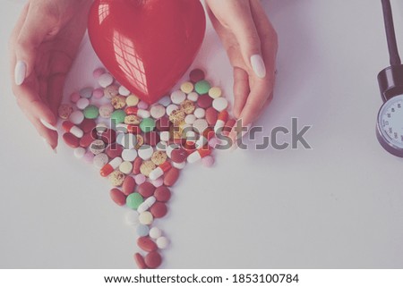 Cardiologist with red heart and stethoscope at table