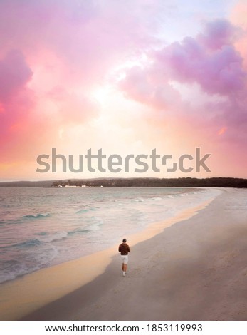 Drone photo with vibrant colourful sky with man standing on long beach in Jervis Bay on the south coast of New South Wales