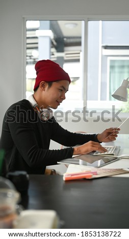 Portrait of graphic designer or photographer is using digitizer and colour sample in his office.