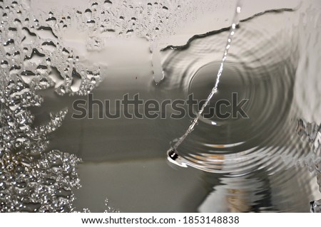 Jet of falling water.  Drops of water on a  glass.