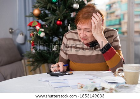 Senior woman engaged in home accounting in the new year holiday. High quality photo