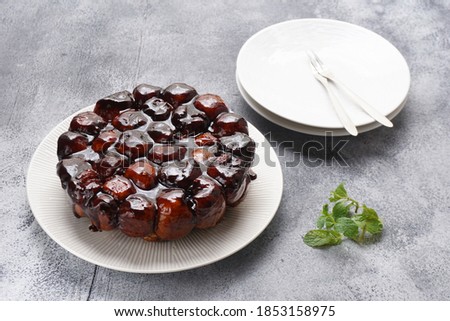 A picture of shiny glaze of Monkey Bread or Cinnamon pull apart bread in grainy texture background in white plate and some Mint leaves. Isolated and copy space background