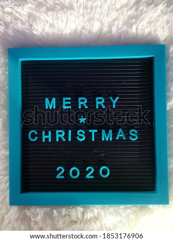 Moveable letters on a square letter board with blue lettering spelling the words Merry Christmas and the year 2020. Marquee with changeable capital letters of the alphabet, numbers and symbols.