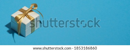White gift box with yellow ribbon bow on blue background with copy space. Christmas banner mockup, header design, greeting card template.