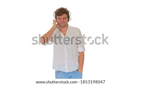 Casual young man listening to music holding headphones by his ha