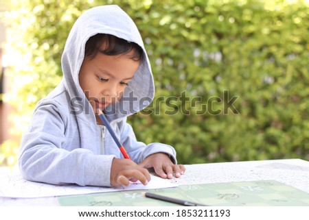 Cute Asian child drawing picture with crayon.