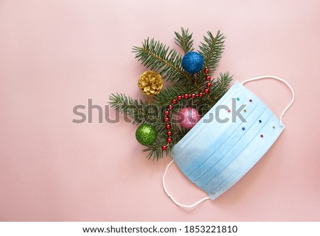 Trendy layout with Christmas tree branches, New Year's decor and face protection mask. Winter holiday season. Healthcare concept.  Flat lay, copy space.