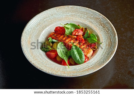 Roasted Salmon steak in tomato sauce with stewed vegetables for garnish. Selective focus, black background