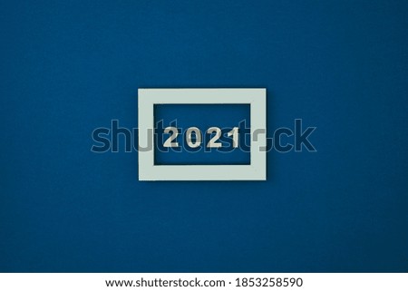 White frame on a blue background and the inscription 2021. New Year's decor. Copy space, mock up.