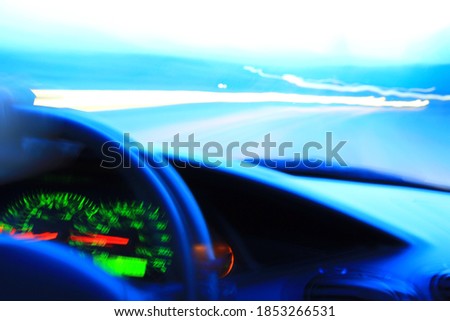 Futuristic presentation of driving. Blurred view of car cabin, a driver and road ahead. Night time.