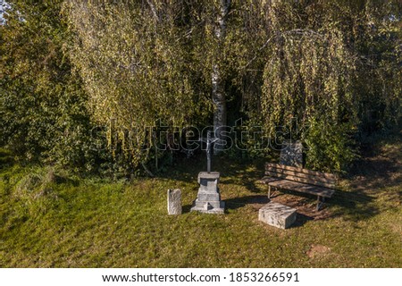 Picture of a wayside cross in front of a big tree with wooden bench in Bavaria, Germany