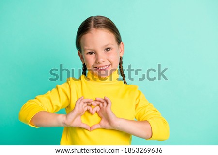 Photo of adorable sweet little girl make hands heart figure wear yellow turtleneck isolated on shine teal color background