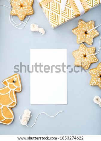 Christmas and New Year frame with blank card, space for text, postcard or invitation. Tasty gingerbread biscuits with sugar icing on light blue background, minimalist winter holiday background.