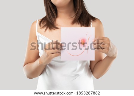 A woman holding a light pink paper with the breast cancer cells picture. Breast tissue. The concept of cancer and healthcare.