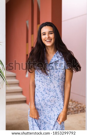 Cute smile pretty caucasian woman in blue dress on background of brown wall 