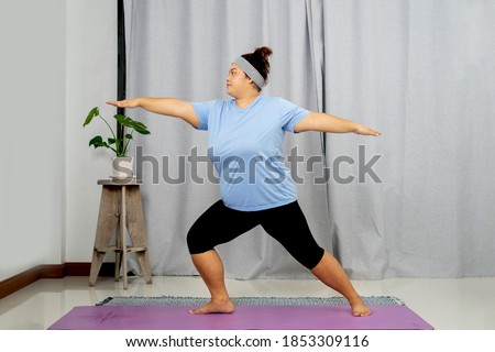 Just keep calm and do sport! Peace rest relaxation vitality concept. Cheerful curvy fatty concentrated oversize with flabby belly woman is doing yoga on purple mat on the floor at home.