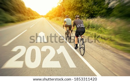 Two cyclist is moving straight to the 2021 year