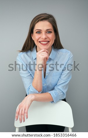 Smiling woman in blue shirt touches her chin. Business woman or student look.