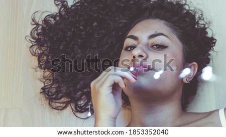 Model with curly hair and brown skin with a white vibe and highlights that enhance her skin tone