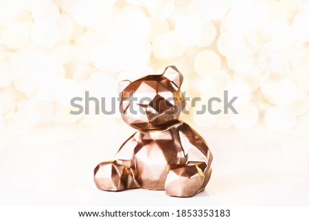 Gift card with chocolate bear on golden background of christmas lights bokeh. Mockup for decorative design. Christmas and New Year concept. Copy space.