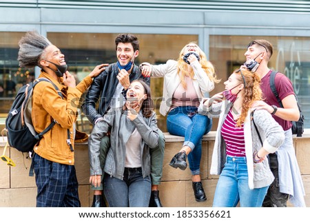 students of different ethnicities joking and laughing together during the epidemic period, irresponsible young people who wear the face mask incorrectly, new normal concept, no social distancing Royalty-Free Stock Photo #1853356621