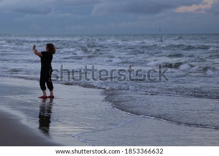 Woman taking a selfie on the seashore.