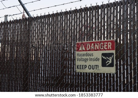 High Voltage Danger sign at the fence of an electrical substation.
