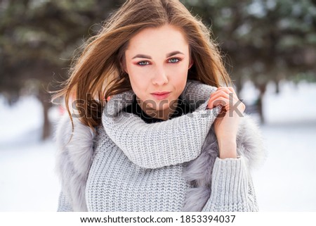 Close up portrait of young woman in gray fur vest, winter outdoors