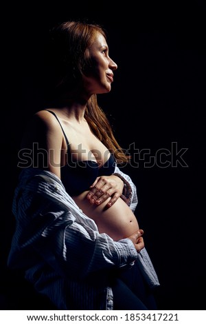 Profile of pregnant woman in bra over black background feeling calmness with closed eyes