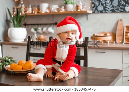 Baby Santa sits in the kitchen of the house, the inscription on a graphic board in Russian the language "happy new year"!