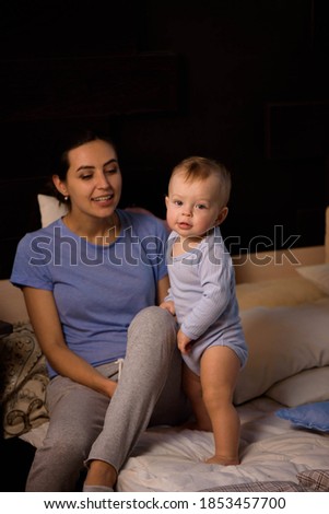 Happy loving family. Mother playing with her baby in the bedroom. Pretty woman holding a newborn baby in her arms