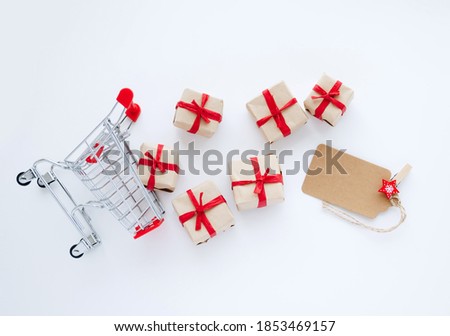 Top view on shopping cart with gifts and blank lable on white background.