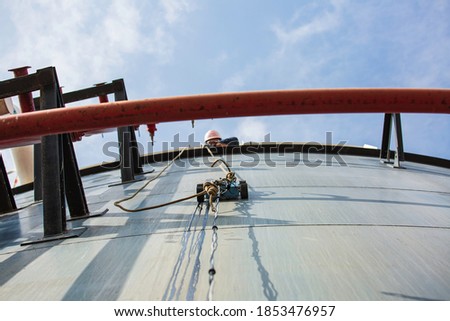 Robot car climbing thickness shell plate storage tank oil below male worker pull the rope