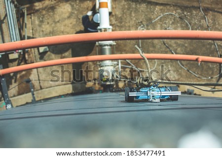 Robot car climbing thickness shell plate storage tank oil below male worker pull the rope
