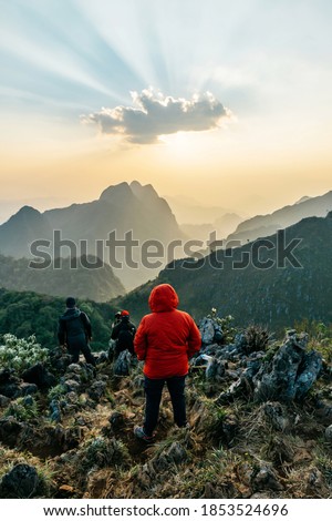 Adventurers wearing a red hoodie with mountains and dusk near the sunset in the background of Doi Luang, Chiang Dao, Chiang Mai, Thailand. Taking a photo from the summit.