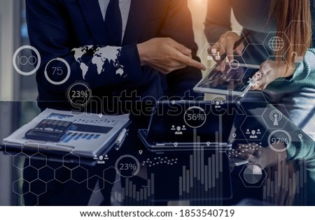 Double exposure of business teamwork working on digital tablet and laptop computer with virtual diagram, graph interfaces icons, Technology digital and stock market concept, Blurred background.