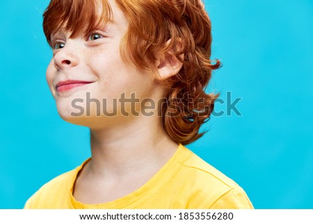 Smiling red-haired boy looking to the side yellow T-shirt studio 