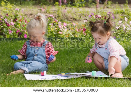Two little girls sisters paint with finger paints