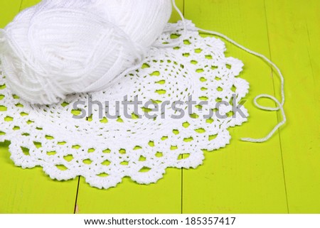White yarn for knitting with napkin and spokes on wooden table close-up