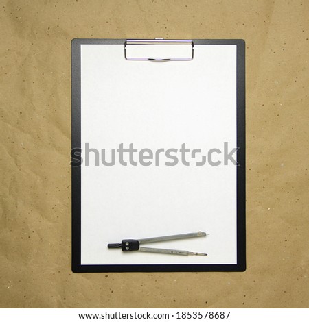 A tablet with a white sheet of A4 format with divivder on a beige craft paper. Concept of accurate measurements, study and construction. Stock photo with empty place for your text and design.