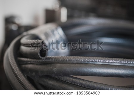 Cut away profile of a door or window automotive style seal. A roll of automotive seals on the floor. Royalty-Free Stock Photo #1853584909