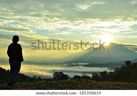 The hopeful Sunrise. Silhouette of a person looking at the sunrises from behind the mountain.  