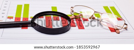 On the table are a magnifying glass, colored reports, and gold-framed glasses. Banner. Business concept
