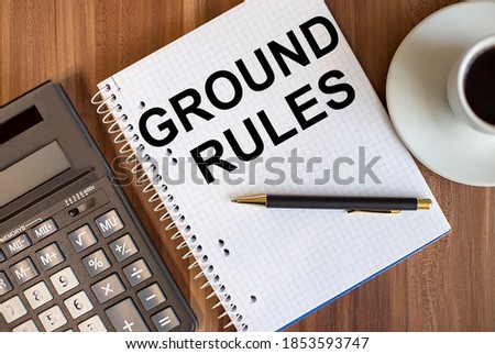 GROUND RULES written in a white notepad near a calculator and a cup of coffee on a dark wooden background