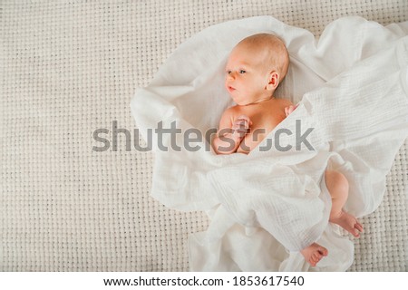 Newborn baby in a white diaper close up. Baby swaddling in muslin diaper and copy space.